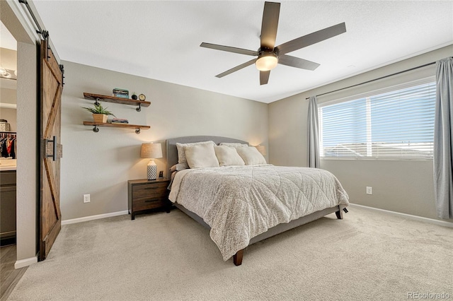 carpeted bedroom featuring a barn door and ceiling fan