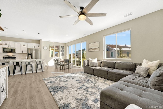 living room featuring light hardwood / wood-style floors and ceiling fan