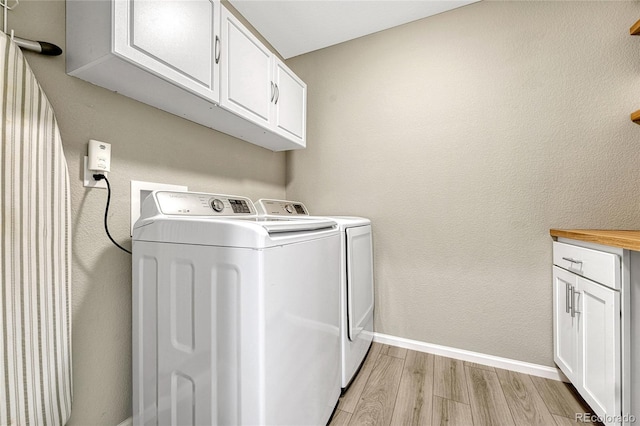 laundry area with cabinets, washer and clothes dryer, and light hardwood / wood-style flooring