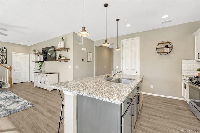 1886 Makley Loop, Castle Rock, CO 80104 - kitchen with stainless steel gas range oven, a sink, light wood-style flooring, baseboards, and a center island with sink