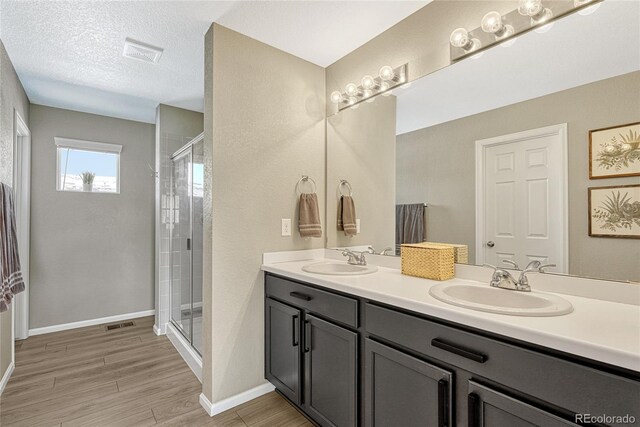 1886 Makley Loop, Castle Rock, CO 80104 - bathroom featuring a shower stall, double vanity, wood finished floors, baseboards, and a textured ceiling
