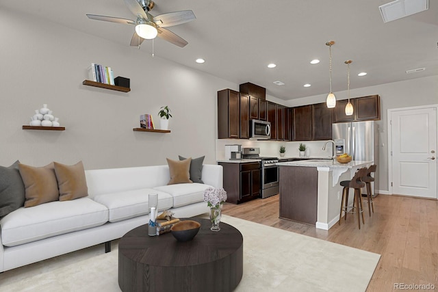 living room with light wood-type flooring, sink, and ceiling fan