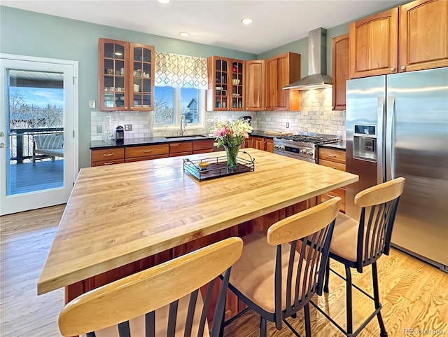 kitchen featuring wood counters, appliances with stainless steel finishes, wall chimney exhaust hood, and a sink