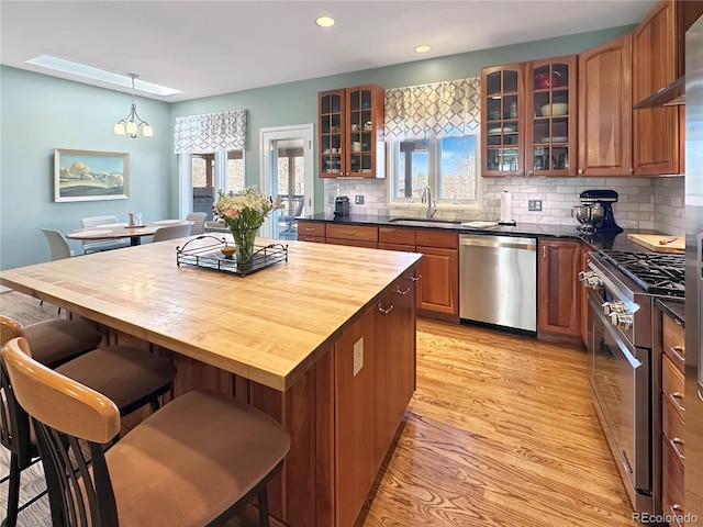 kitchen with a breakfast bar area, a sink, light wood-style floors, appliances with stainless steel finishes, and butcher block counters