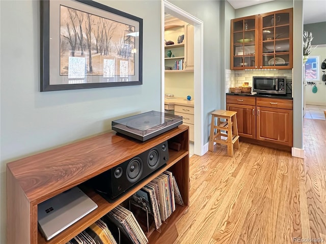 interior space with stainless steel microwave, decorative backsplash, and wood finished floors