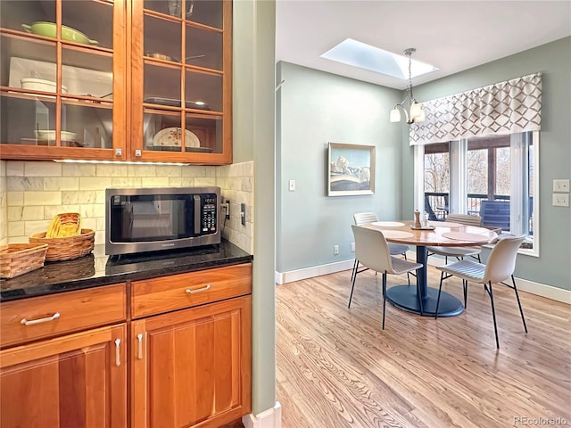 dining space with light wood-type flooring, baseboards, and a skylight