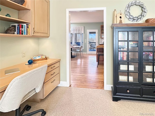 office area with baseboards, built in desk, and light wood-type flooring