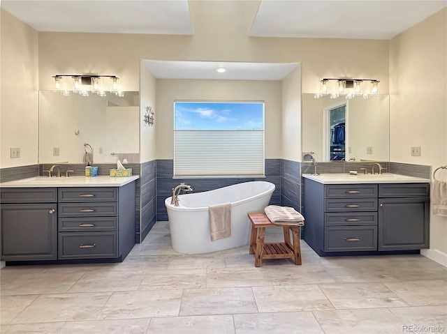 full bath with tile walls, a freestanding bath, two vanities, and a sink