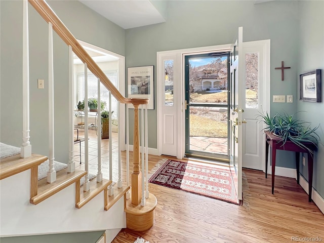 entryway with baseboards, light wood-style flooring, and stairs