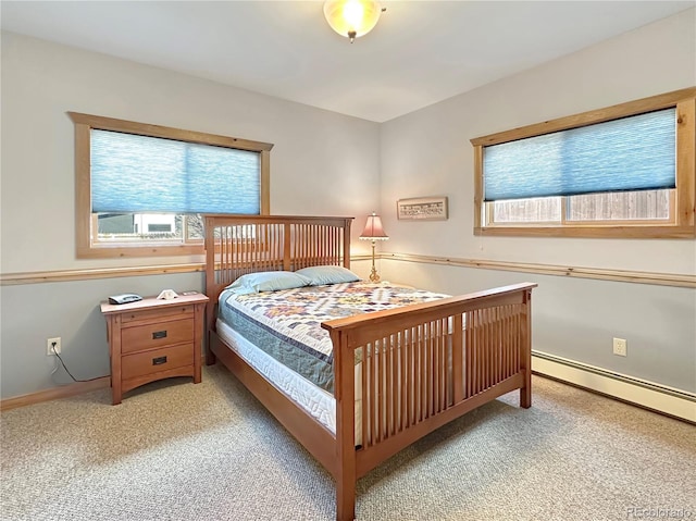 bedroom with baseboard heating, multiple windows, light colored carpet, and baseboards