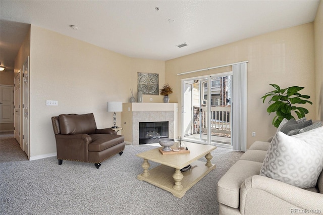 living room with baseboards, a tiled fireplace, visible vents, and light colored carpet