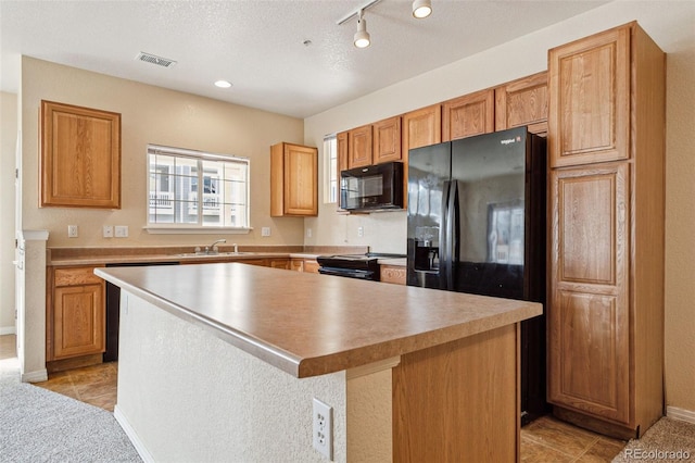 kitchen featuring a center island, visible vents, a sink, a textured ceiling, and black appliances