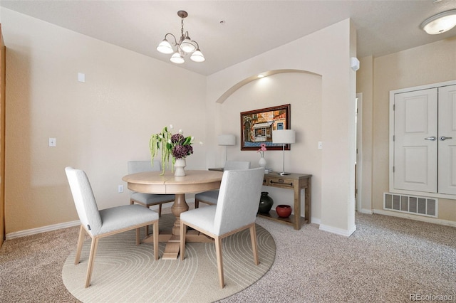 dining space featuring a chandelier, visible vents, light carpet, and baseboards