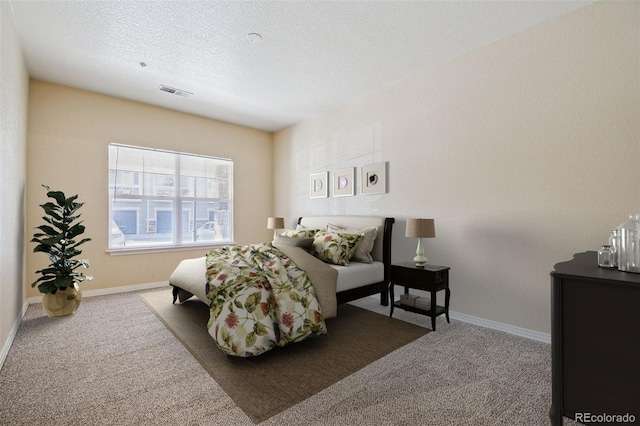 carpeted bedroom featuring baseboards, visible vents, and a textured ceiling