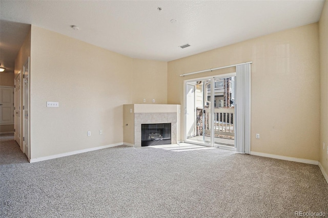 unfurnished living room featuring carpet, visible vents, baseboards, and a tiled fireplace