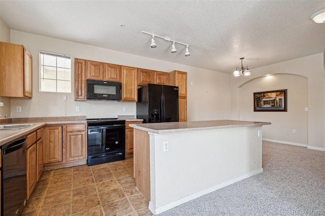 kitchen featuring a kitchen island, light countertops, black appliances, pendant lighting, and a sink