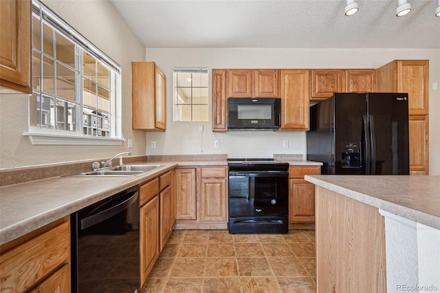 kitchen with brown cabinetry, light countertops, a textured ceiling, black appliances, and a sink