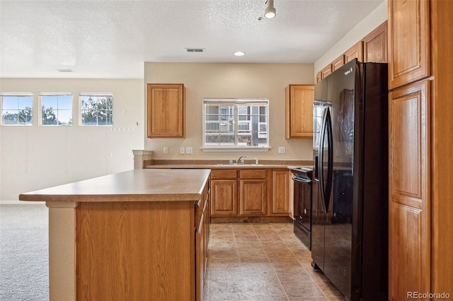 kitchen with range with electric cooktop, a kitchen island, visible vents, light countertops, and black fridge