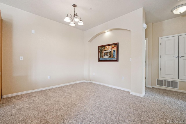 spare room featuring baseboards, carpet flooring, visible vents, and a notable chandelier