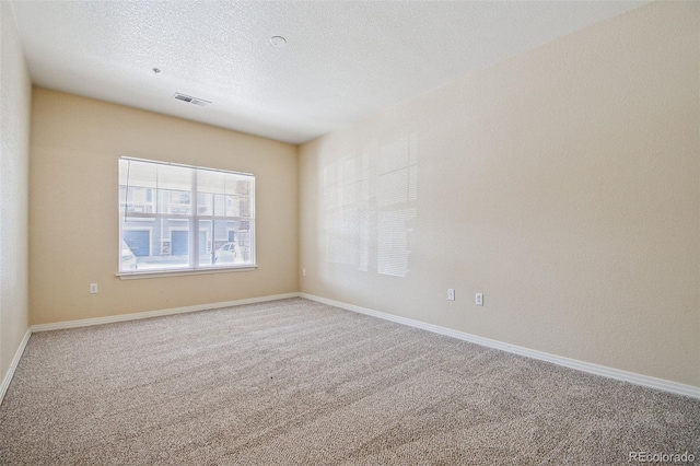 unfurnished room featuring a textured ceiling, carpet, visible vents, and baseboards