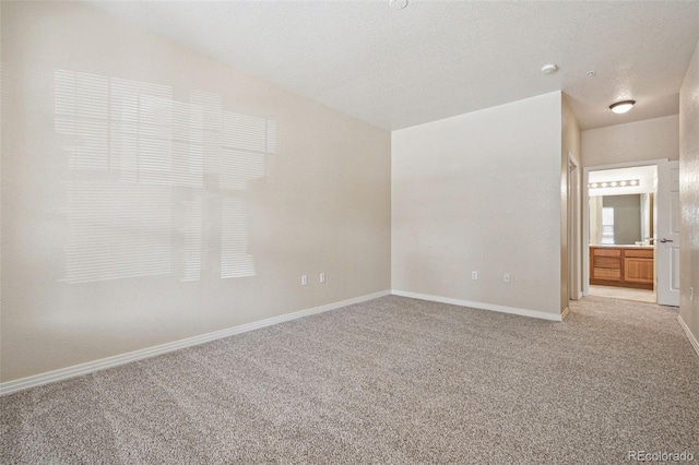 empty room featuring light carpet, baseboards, and a textured ceiling