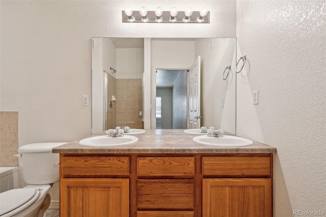 full bathroom featuring a textured wall, double vanity, tiled shower, and a sink