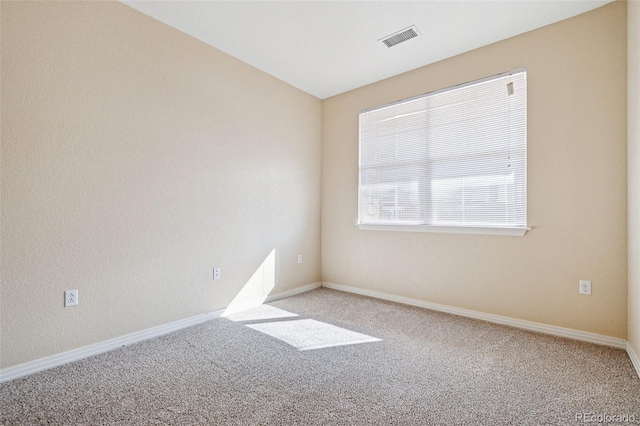 carpeted spare room with visible vents and baseboards