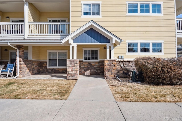 view of exterior entry with a balcony and stone siding