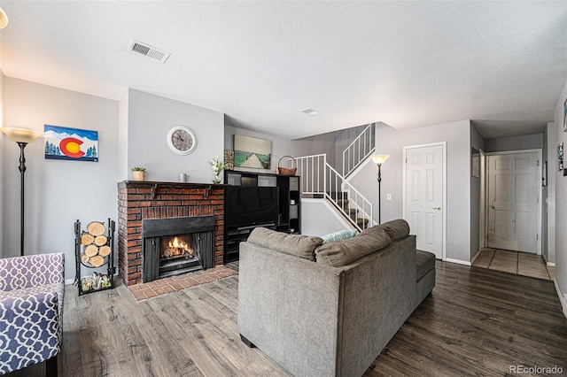 living room with visible vents, a fireplace, wood finished floors, and stairs