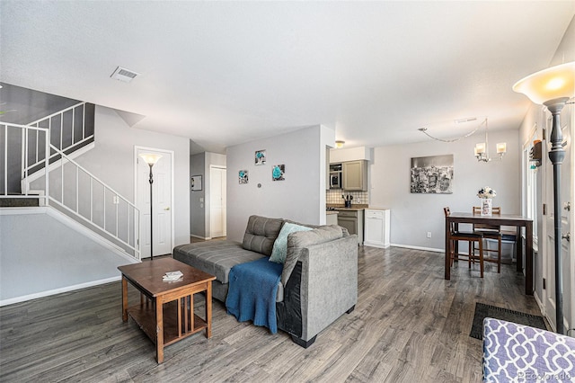 living area featuring visible vents, stairway, baseboards, and wood finished floors