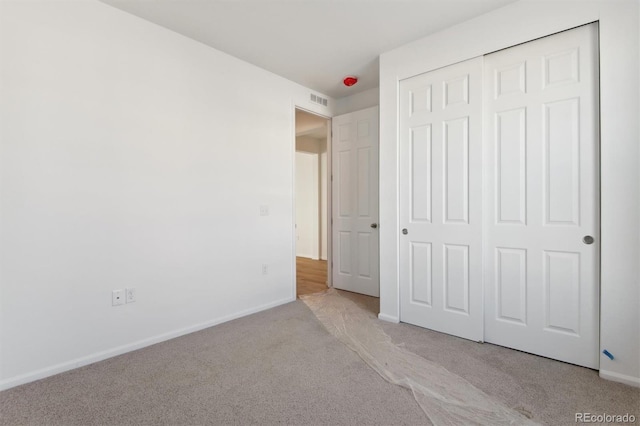 unfurnished bedroom with light colored carpet and a closet