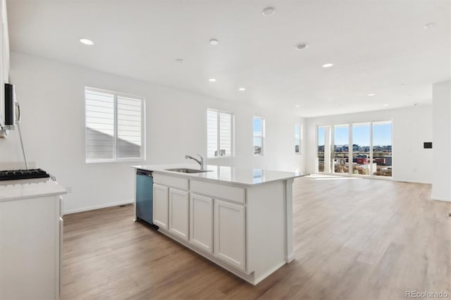 kitchen with white cabinets, appliances with stainless steel finishes, a center island with sink, and a wealth of natural light