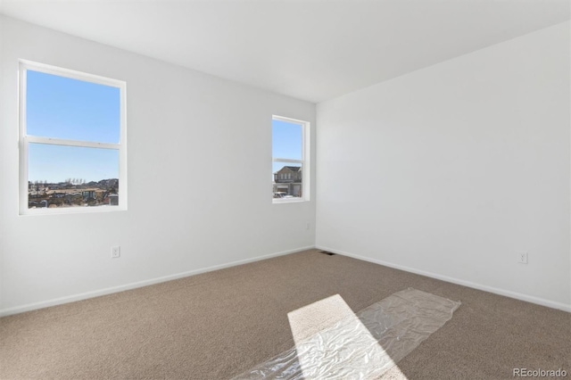 carpeted spare room featuring a wealth of natural light