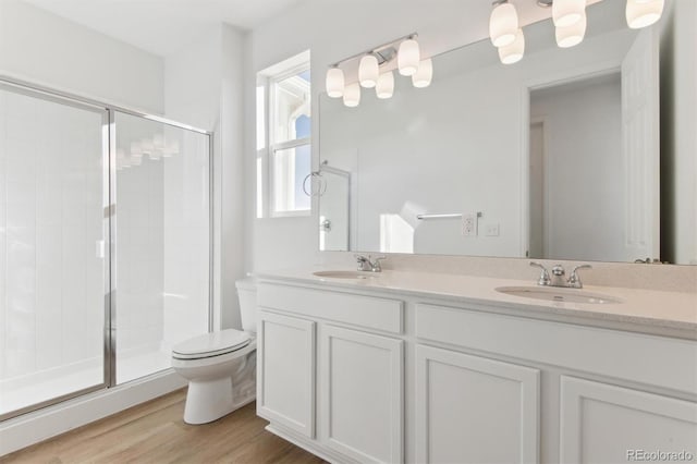 bathroom featuring hardwood / wood-style floors, vanity, a shower with door, and toilet