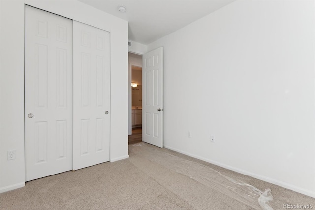 unfurnished bedroom with light colored carpet and a closet