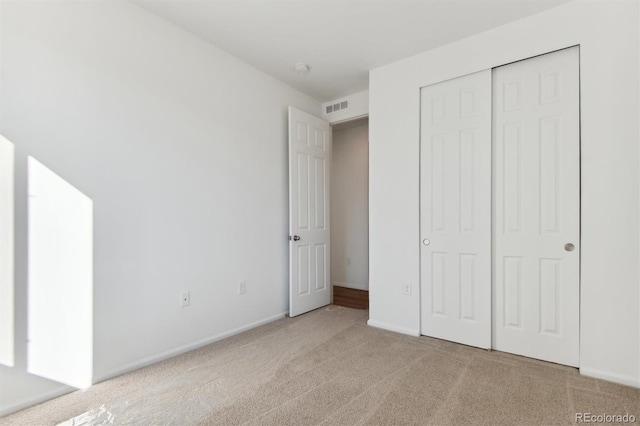 unfurnished bedroom featuring a closet and light colored carpet