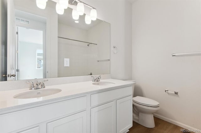 bathroom with hardwood / wood-style flooring, vanity, toilet, and walk in shower