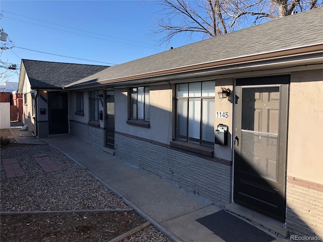 1143 Akron St, Aurora, CO 80010 - back of house featuring brick siding, roof with shingles, and stucco siding