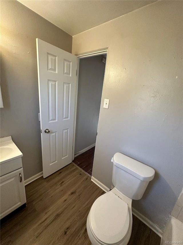 1143 Akron St, Aurora, CO 80010 - bathroom with wood finished floors, baseboards, toilet, and vanity