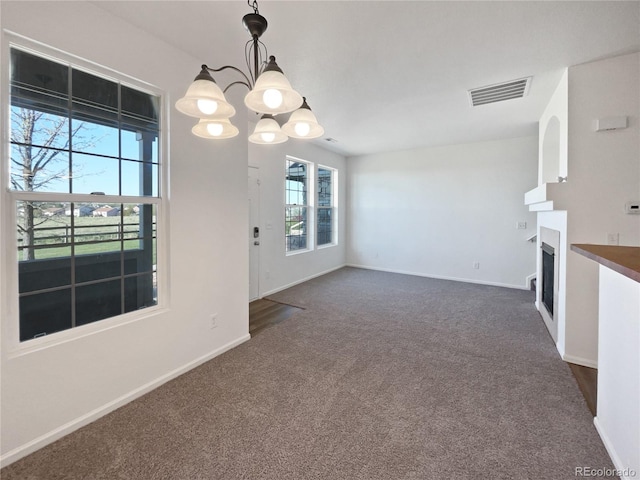 12713 Leyden St Unit E, Thornton, CO 80602 - unfurnished living room with dark colored carpet, a chandelier, baseboards, and a fireplace