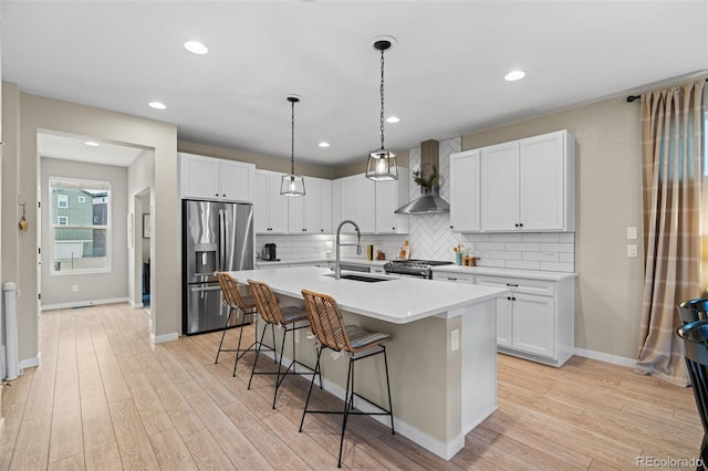 kitchen featuring white cabinetry, sink, wall chimney range hood, and appliances with stainless steel finishes