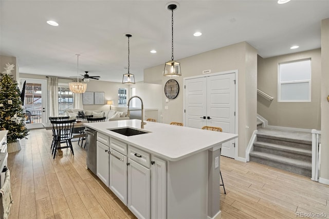 kitchen with dishwasher, a kitchen island with sink, sink, ceiling fan, and light hardwood / wood-style floors