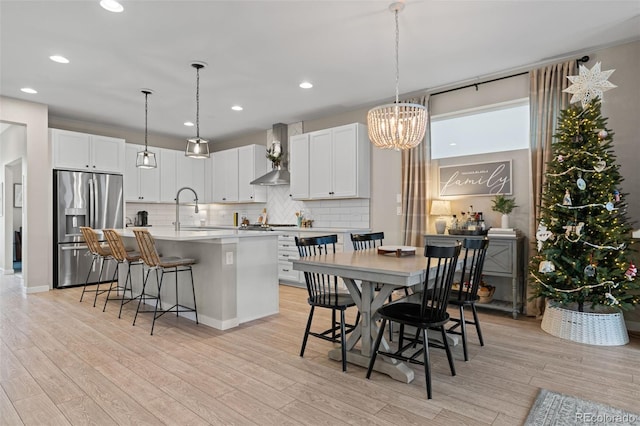 kitchen featuring a center island with sink, light wood-type flooring, stainless steel fridge with ice dispenser, and sink