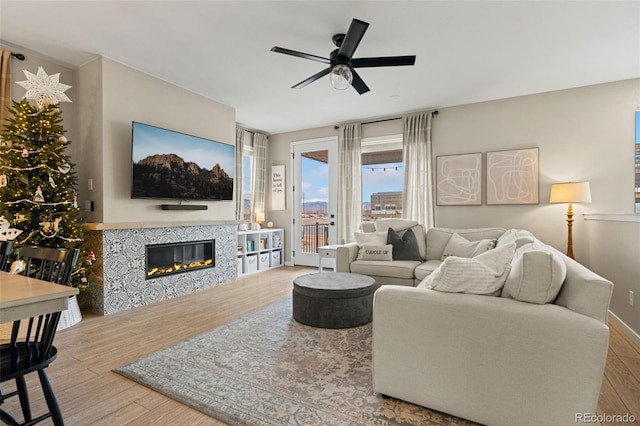 living room with a tiled fireplace, ceiling fan, and hardwood / wood-style flooring