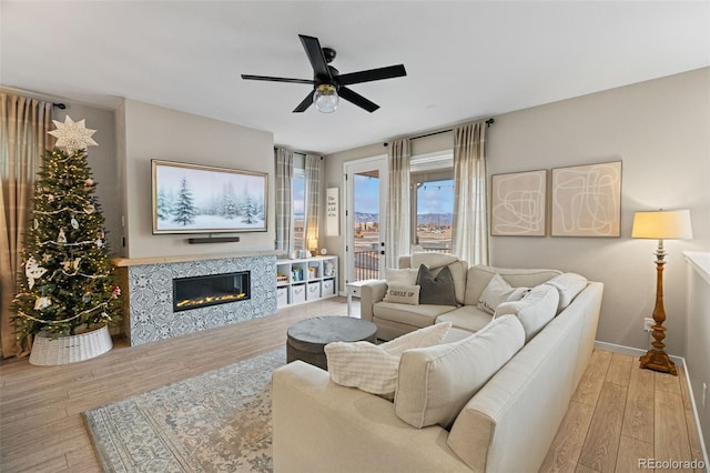 living room with a tile fireplace, light hardwood / wood-style flooring, and ceiling fan