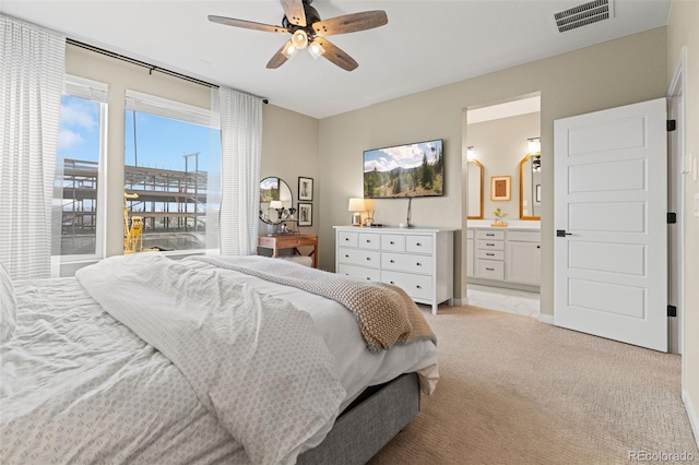 carpeted bedroom with ensuite bath and ceiling fan