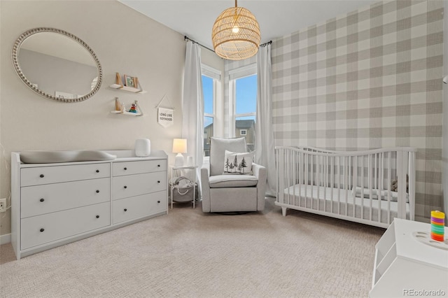 bedroom with light carpet and a nursery area