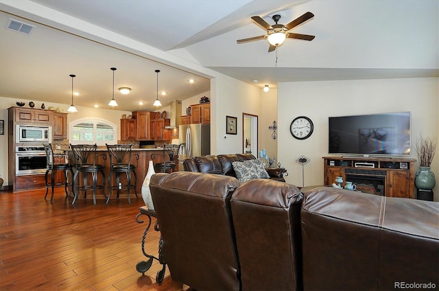 living room featuring ceiling fan, vaulted ceiling, and dark hardwood / wood-style floors