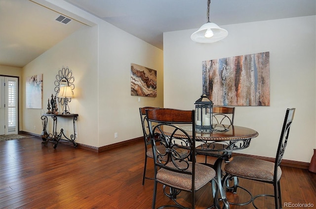 dining room with vaulted ceiling and dark hardwood / wood-style flooring