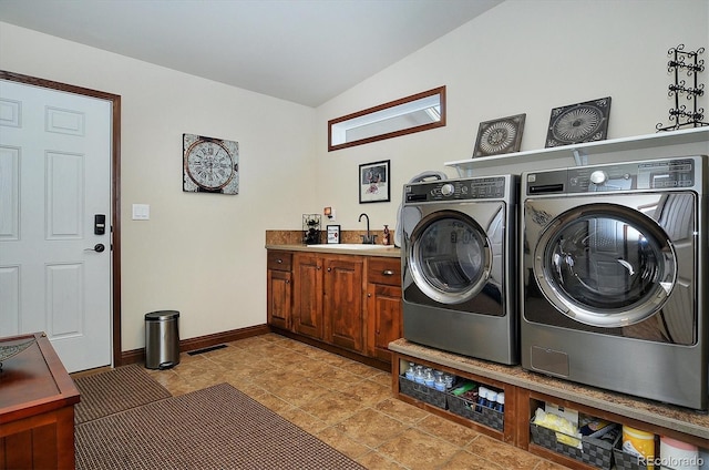 washroom featuring sink, washing machine and dryer, and cabinets